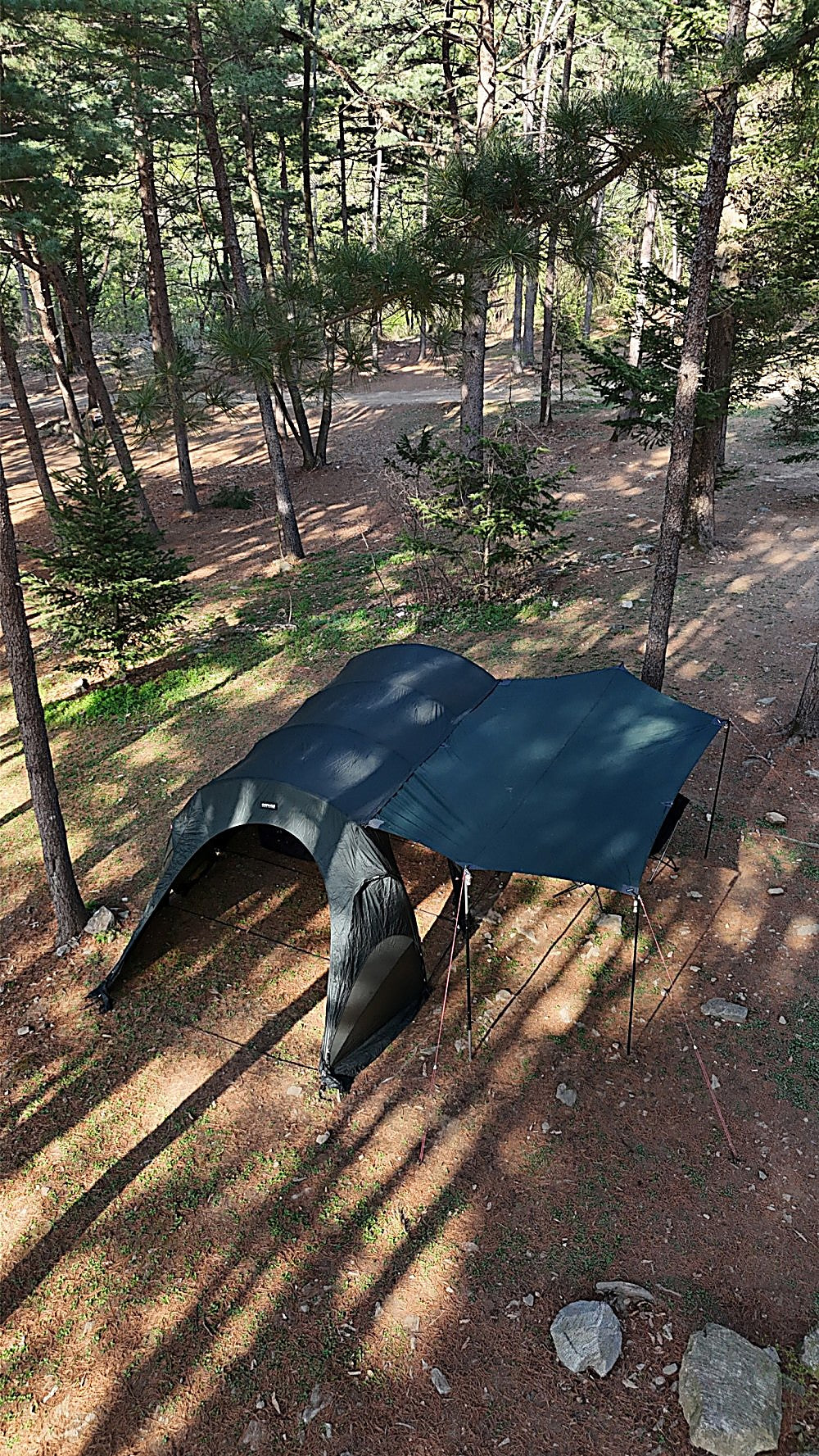 Aerial view of the Gopamir T720+ tent with black-coated side tarp extended flat over the forest floor