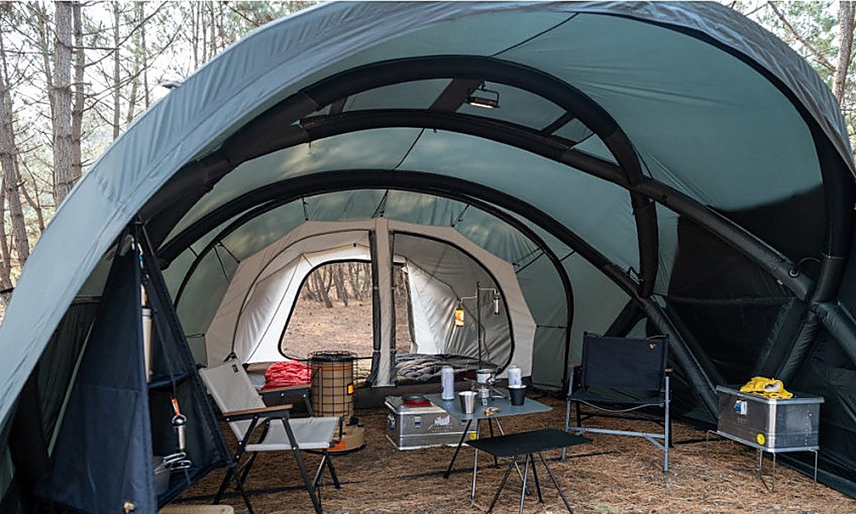 Shelter GM interior looking toward the white inner-tent doorway, arched tunnel frame overhead with camp furniture