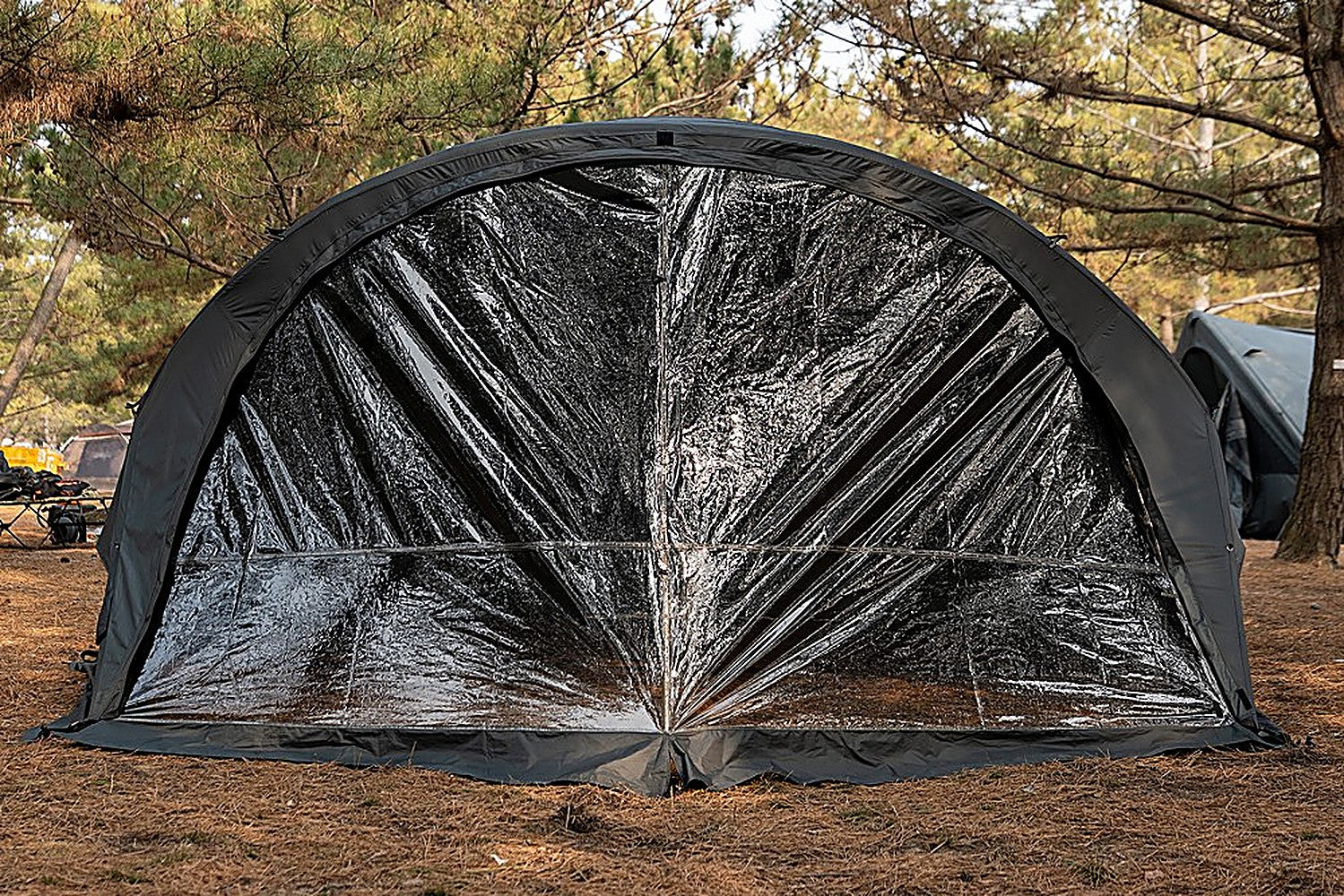 Front view of the transparent Shelter GM TPU Door zipped across the tent's full arched entrance at a forest campsite