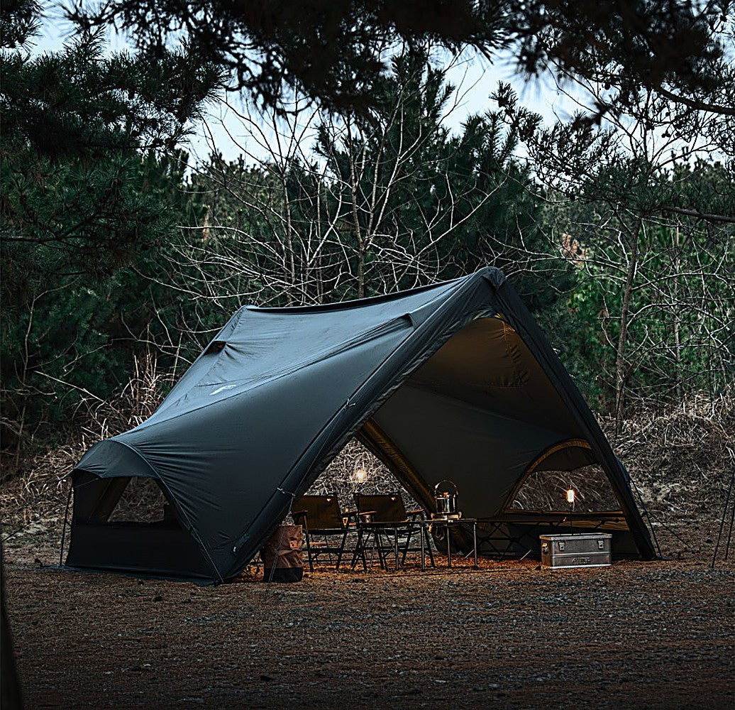 Dusk view of the black Super Position shelter, MGX-600 TPU Door aglow with lantern light over camp chairs and a table