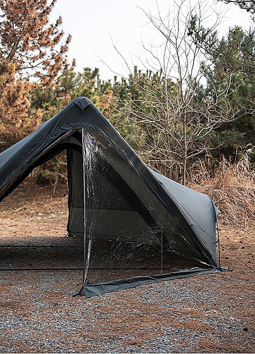 Close-up of the clear MGX-600 TPU Door panel sealing the shelter end, staked taut on a gravel campsite