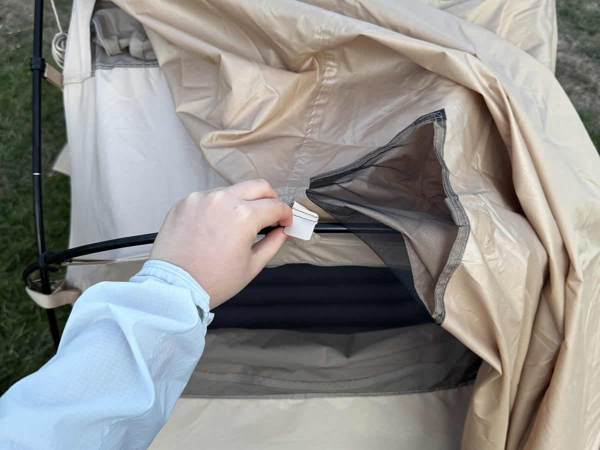 Clipping a Neo Nest 80 corner tab to the cot frame during set-up (cot sold separately).