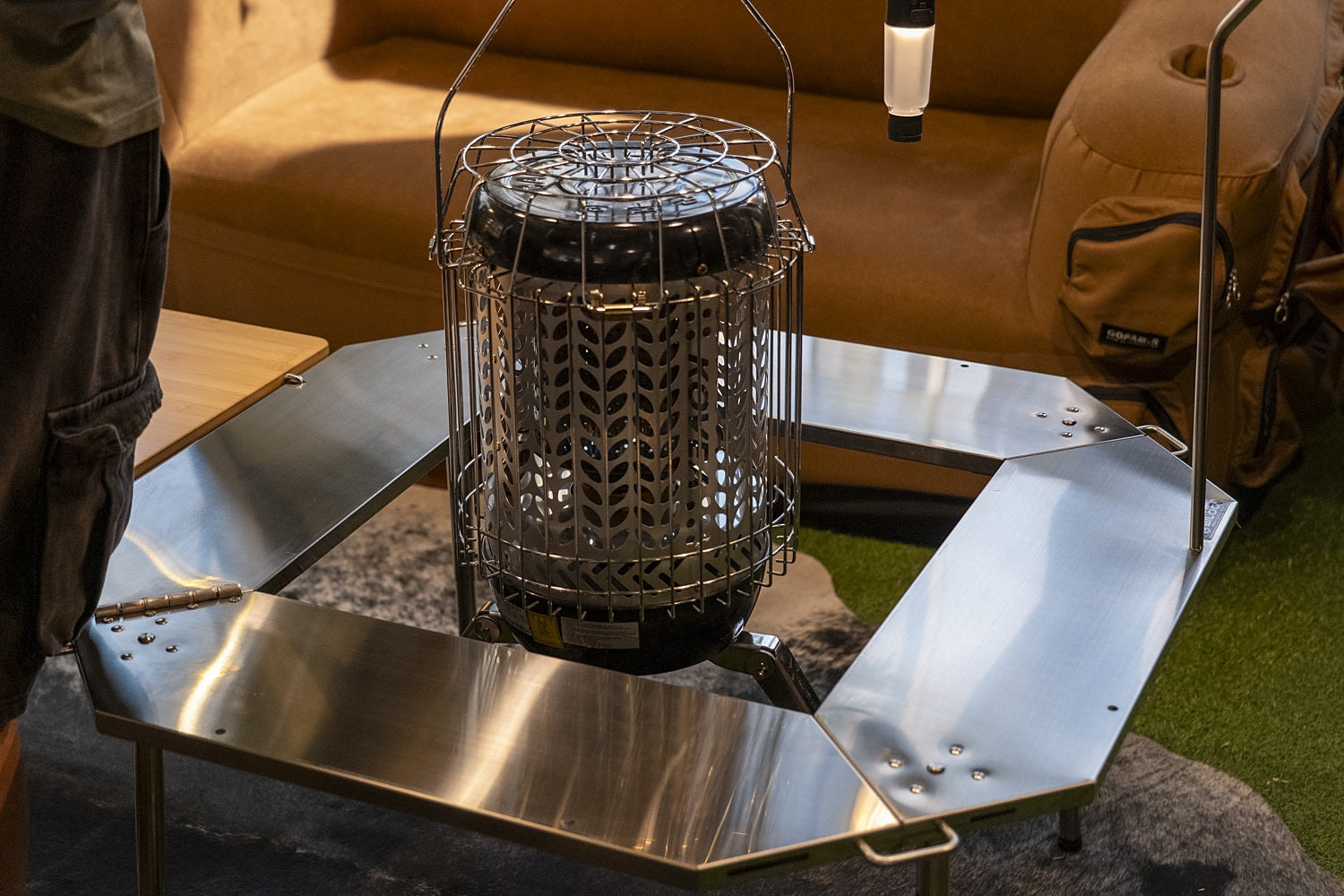 Tall cylindrical camp heater standing in the open centre of the Octa table ring. The heater, lantern and pack shown are not included.
