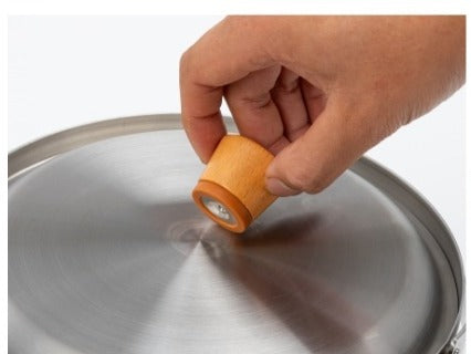 Hand attaching the magnetic wood handle to the pot lid