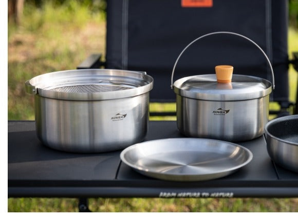 Full cookware set arranged on a camp table, ready for cooking