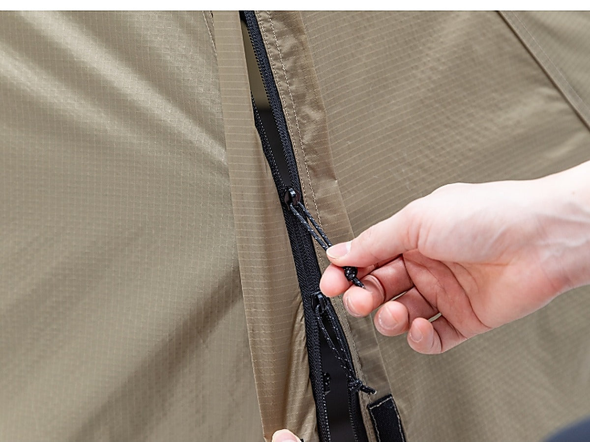 Hand opening the 2-way zipper on the tent door