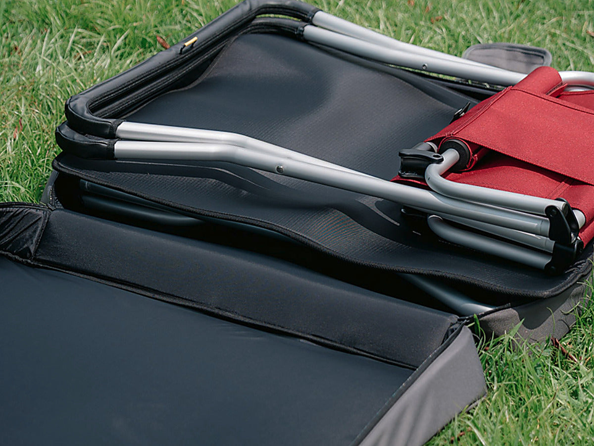 Open CORDURA FD Chair Case on grass showing the thick foam-padded panel and a folded chair resting inside
