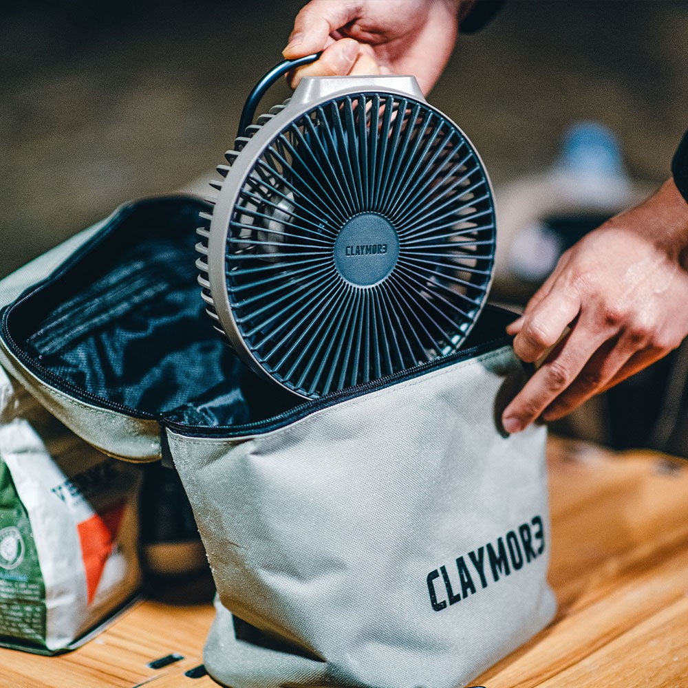 Hands pulling the V600+ fan out of its zippered storage case on a camp table