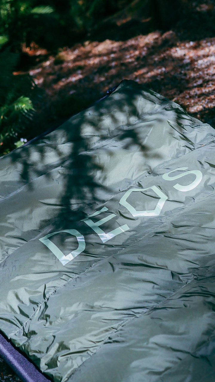 Field-tester photo — olive DEOS Eco-Down Camp Comforter 500 on a cot at a forest campsite