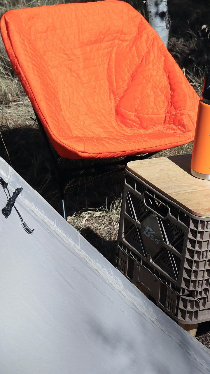 Field-tester photo — orange DEOS Chair Warmer draped over a camp chair at a campsite