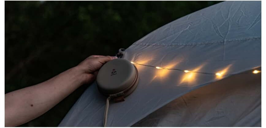 Hand attaching the lantern to a tent using its built-in magnets