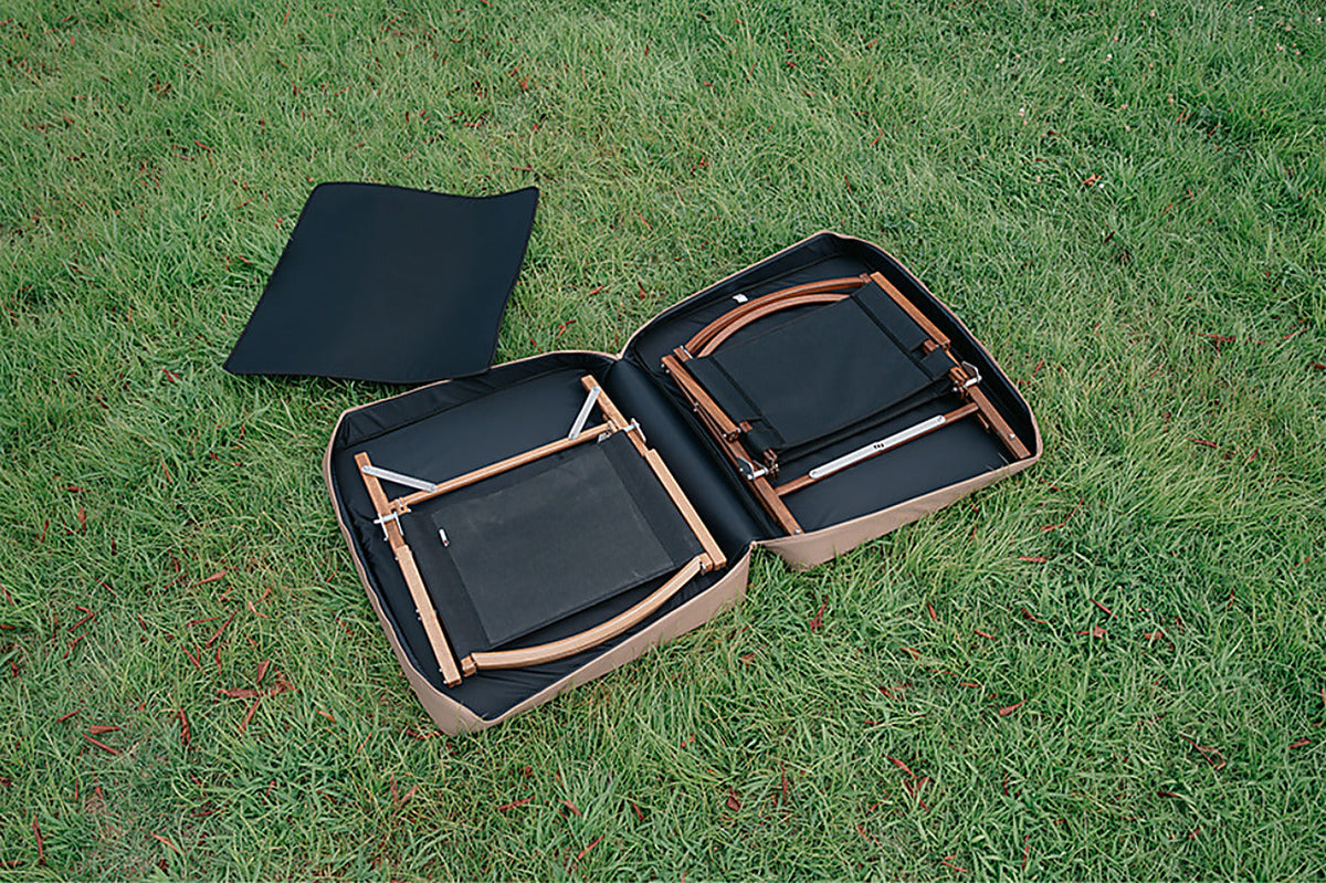 Coyote Tan CORDURA FD Chair Case opened on grass with two folded wood-frame chairs inside