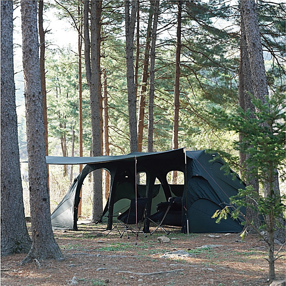 T720+ black side tarp awning sheltering chairs at the tent entrance, seen through sunlit pine trunks