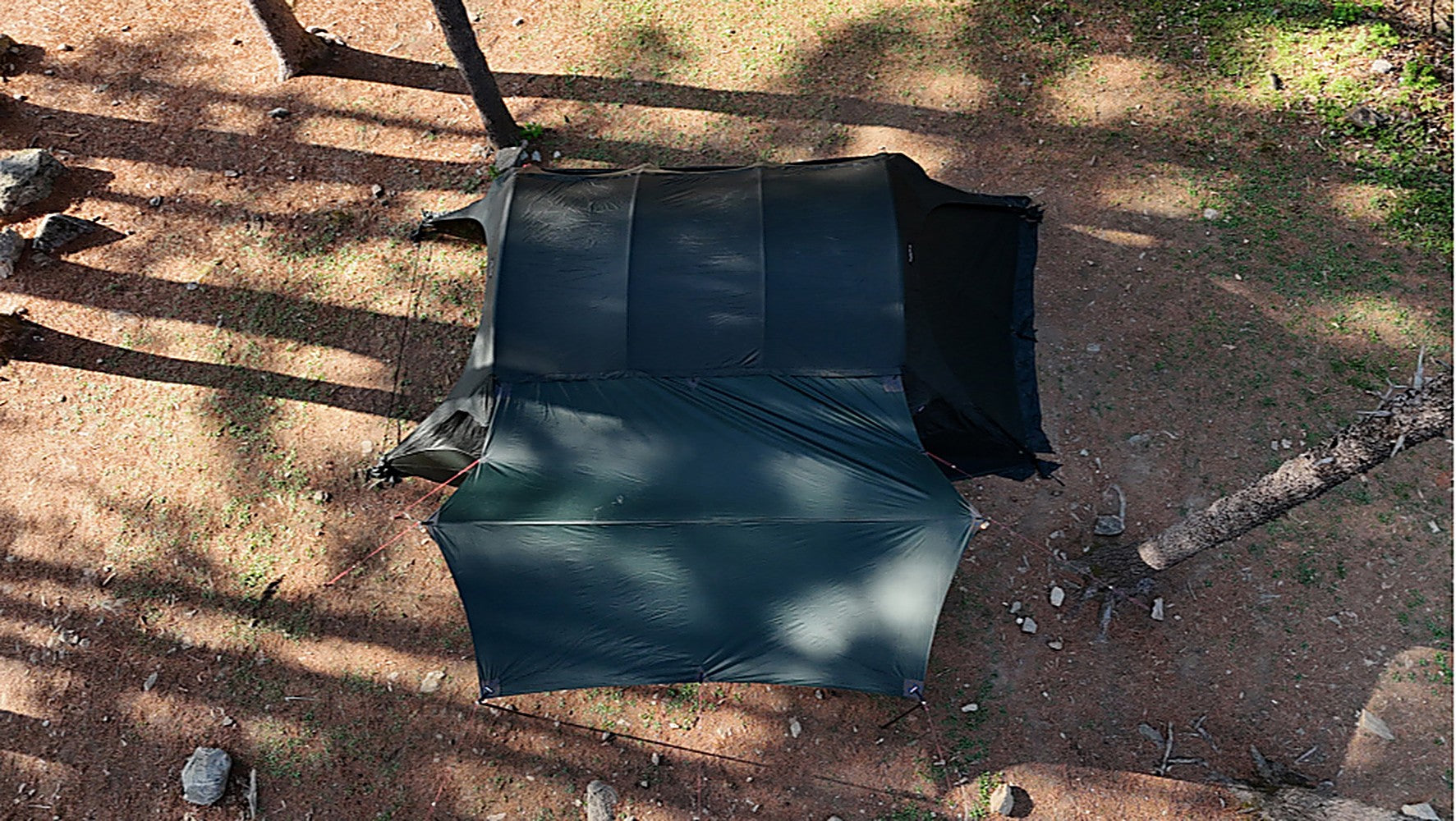 Top-down view of the dark black-coated side tarp and shelter on the forest floor