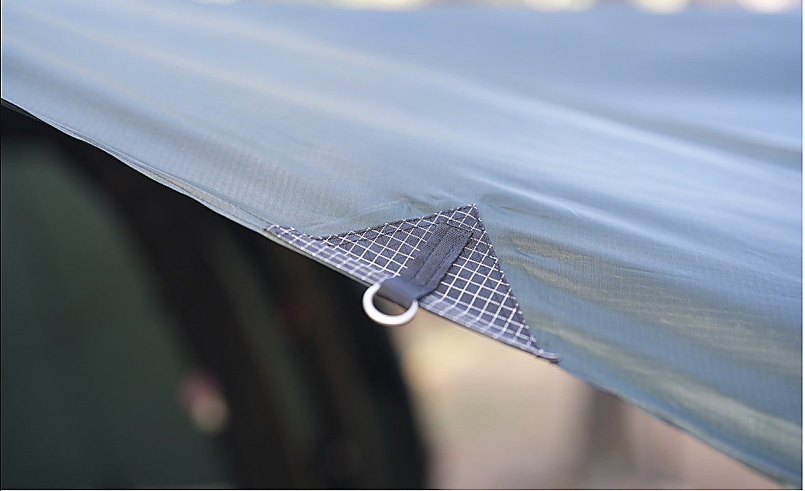Close-up of a reinforced edge O-ring guy-out point on the side tarp for tensioning