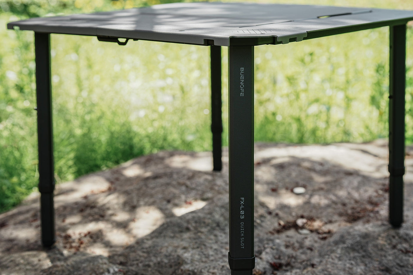 Close-up of a BUENOFE IGT Connect Table 1.5 standalone table from below, focusing on a black quick-slot leg engraved FX-L03 QUICK SLOT and the frame corner it locks into.