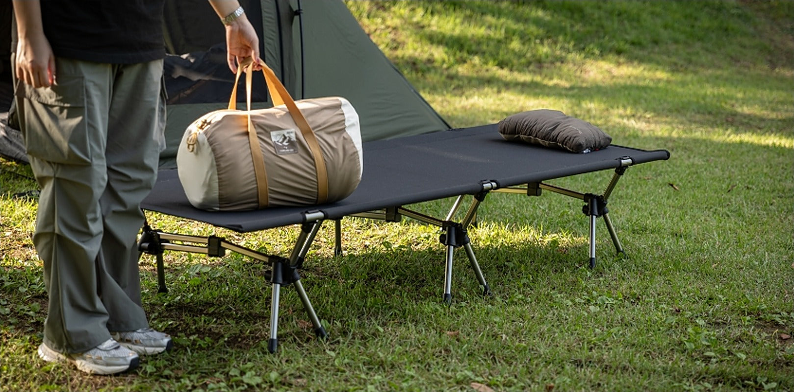 Carrying a duffel bag beside the set-up cot