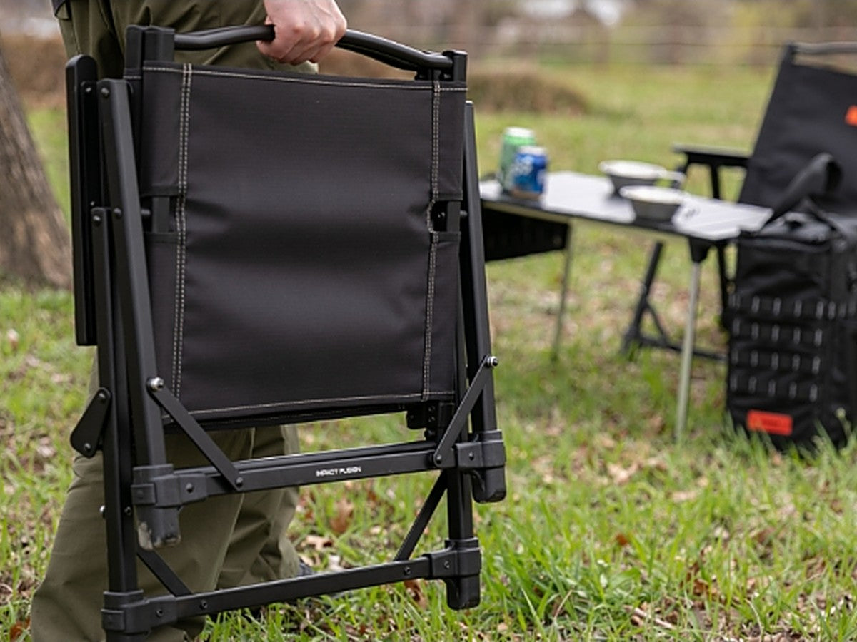 Person carrying the folded Impact Fusion Chair one-handed by its handle