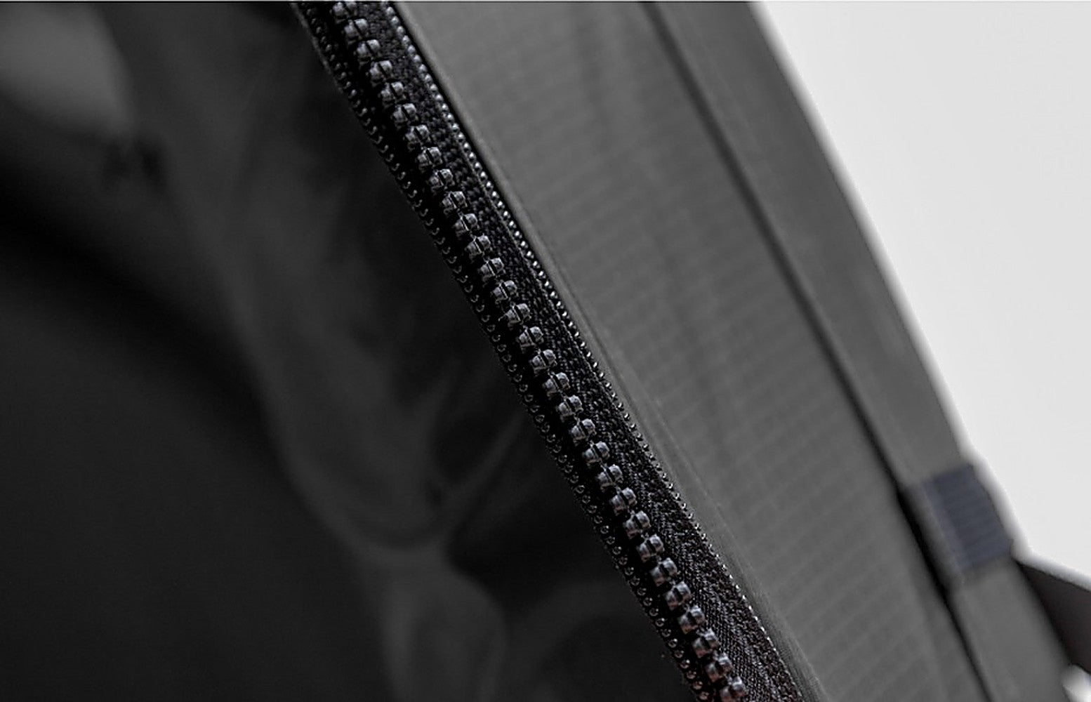 Macro detail of the black zipper coil on the Ghost Phantom Air TPU Side Extension's gray ripstop fabric