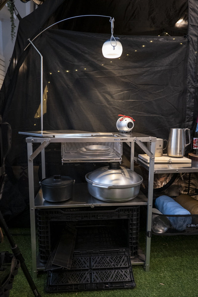The lantern hanger mounted on a Biloc Stella camp shelf, lantern lit above the loaded top.