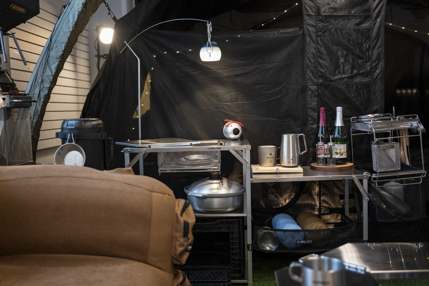 A camp kitchen at night: the lantern hanger arches over the shelf and lights the whole work area.