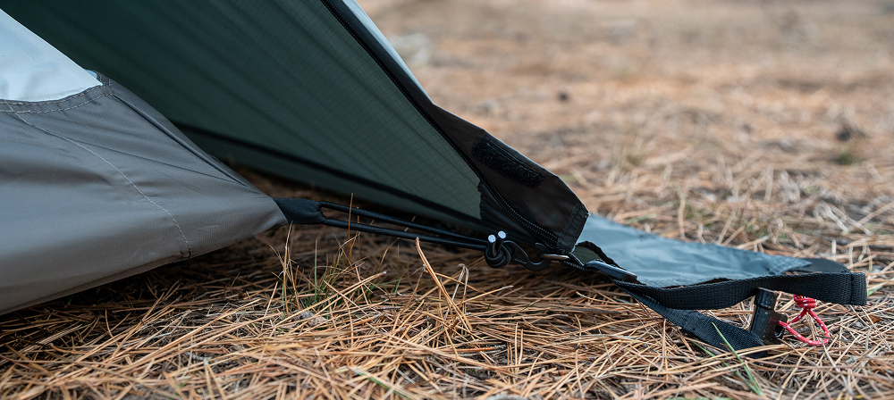 Edge of the inner tent's sewn-in bathtub-style floor meeting the ground over pine needles