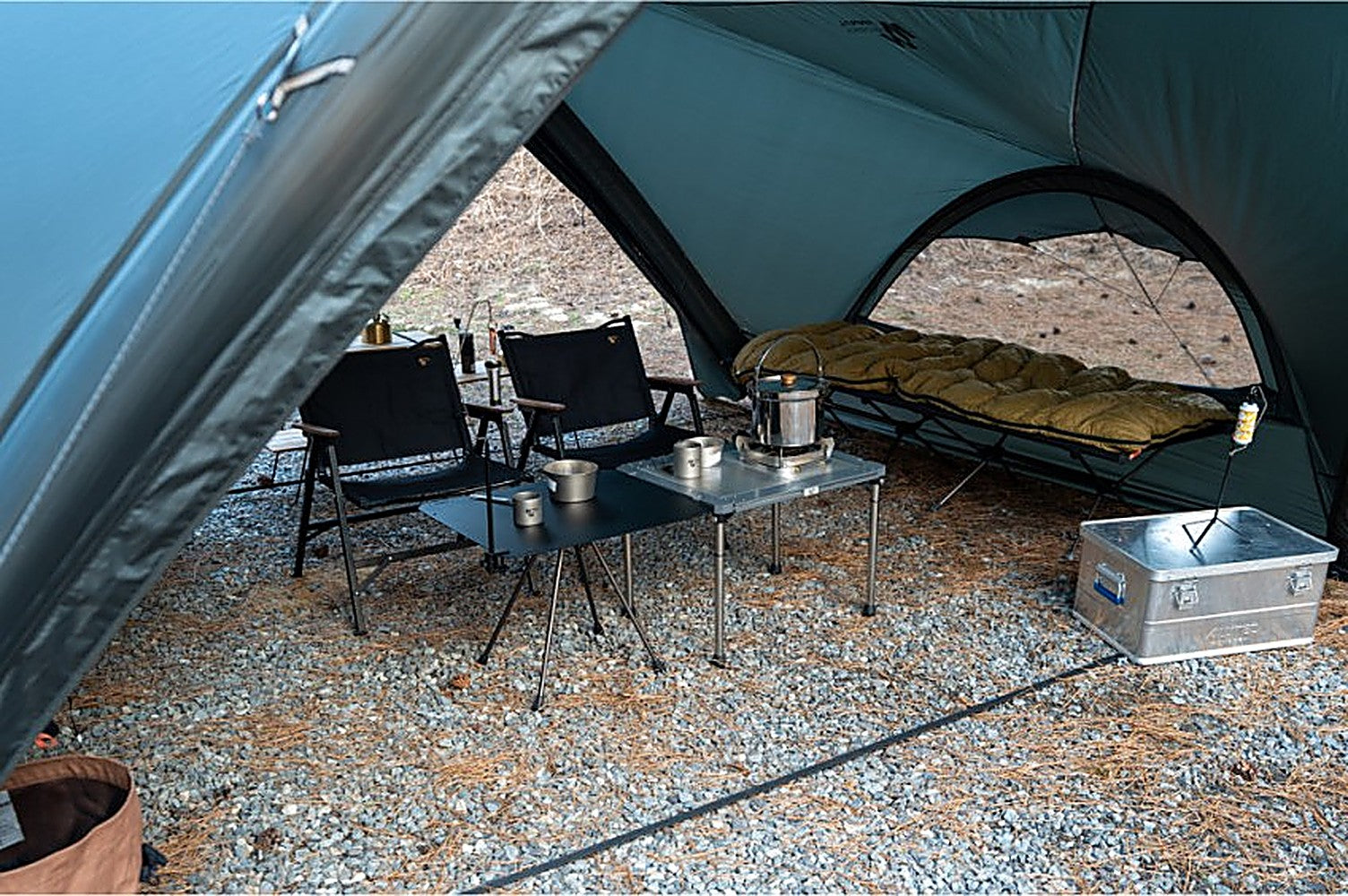 Under the Super Position MGX-600 canopy: camp chairs, low tables, and a cot in the inner mesh room on gravel