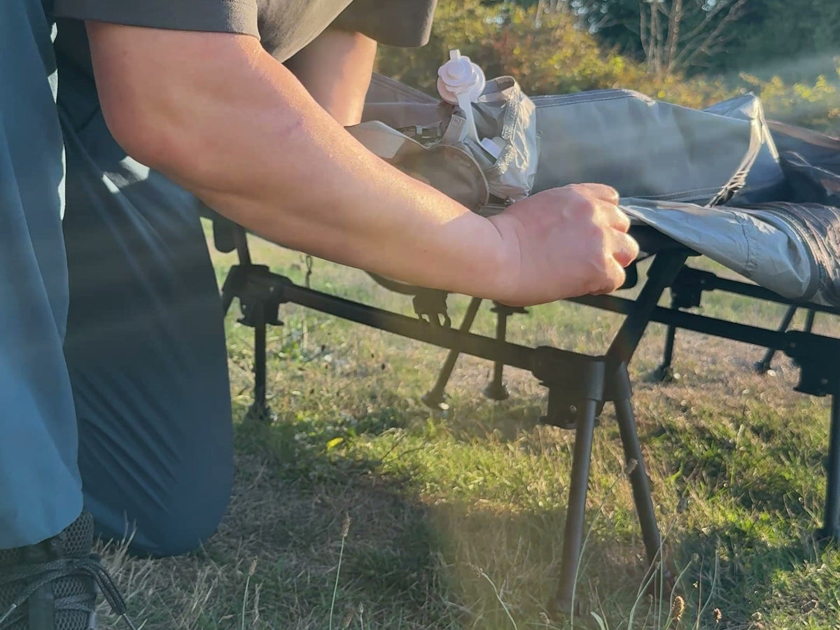 Tightening the Neo Nest 80 Air corner strap under the frame of a camp cot (cot sold separately).