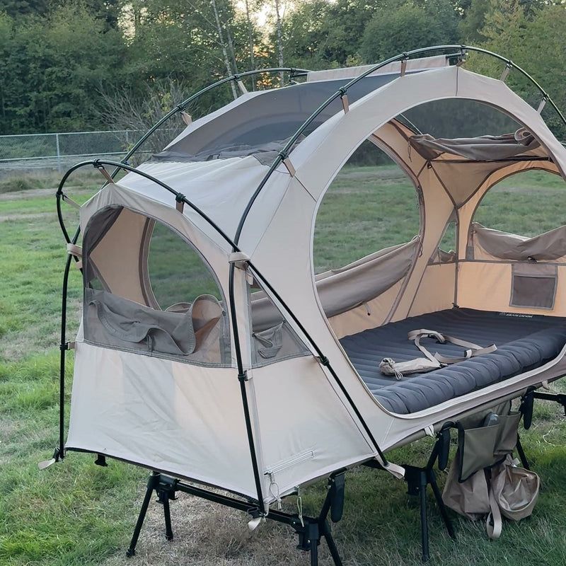 Neo Nest 80 cot tent on a camp cot in a field, both side doors open and a sleeping pad inside (cot and pad sold separately).