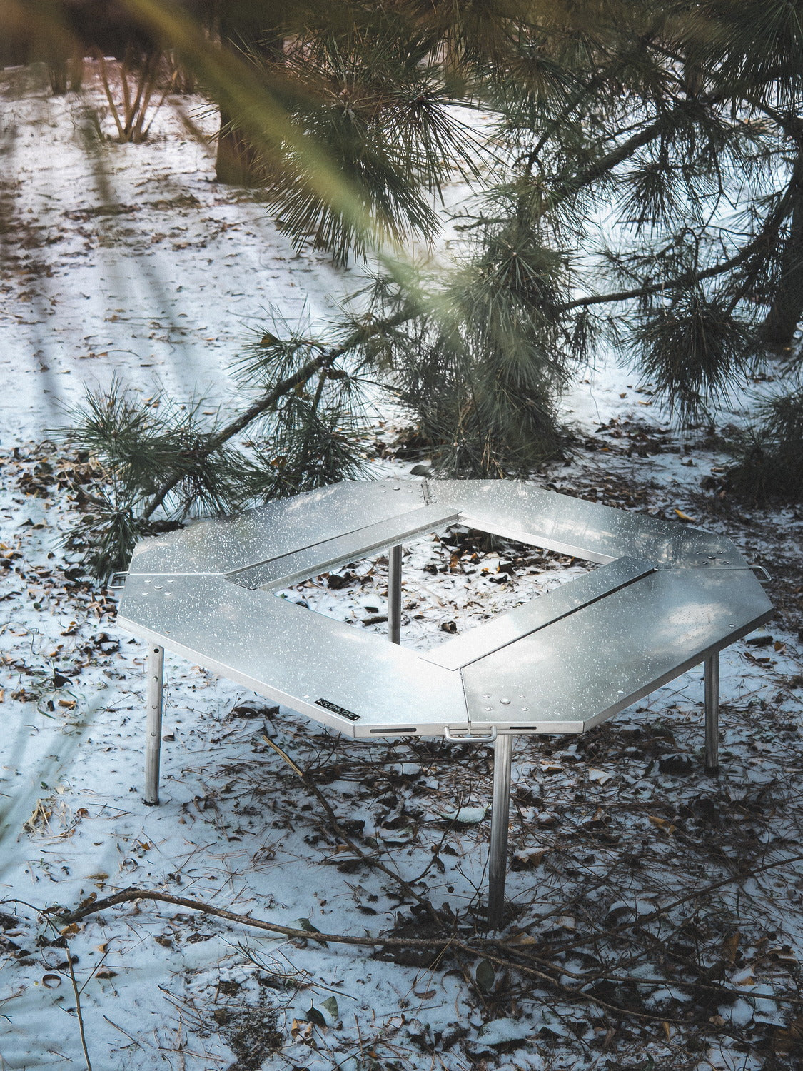 Biloc Octa IGT fire ring table at a winter campsite under pine trees