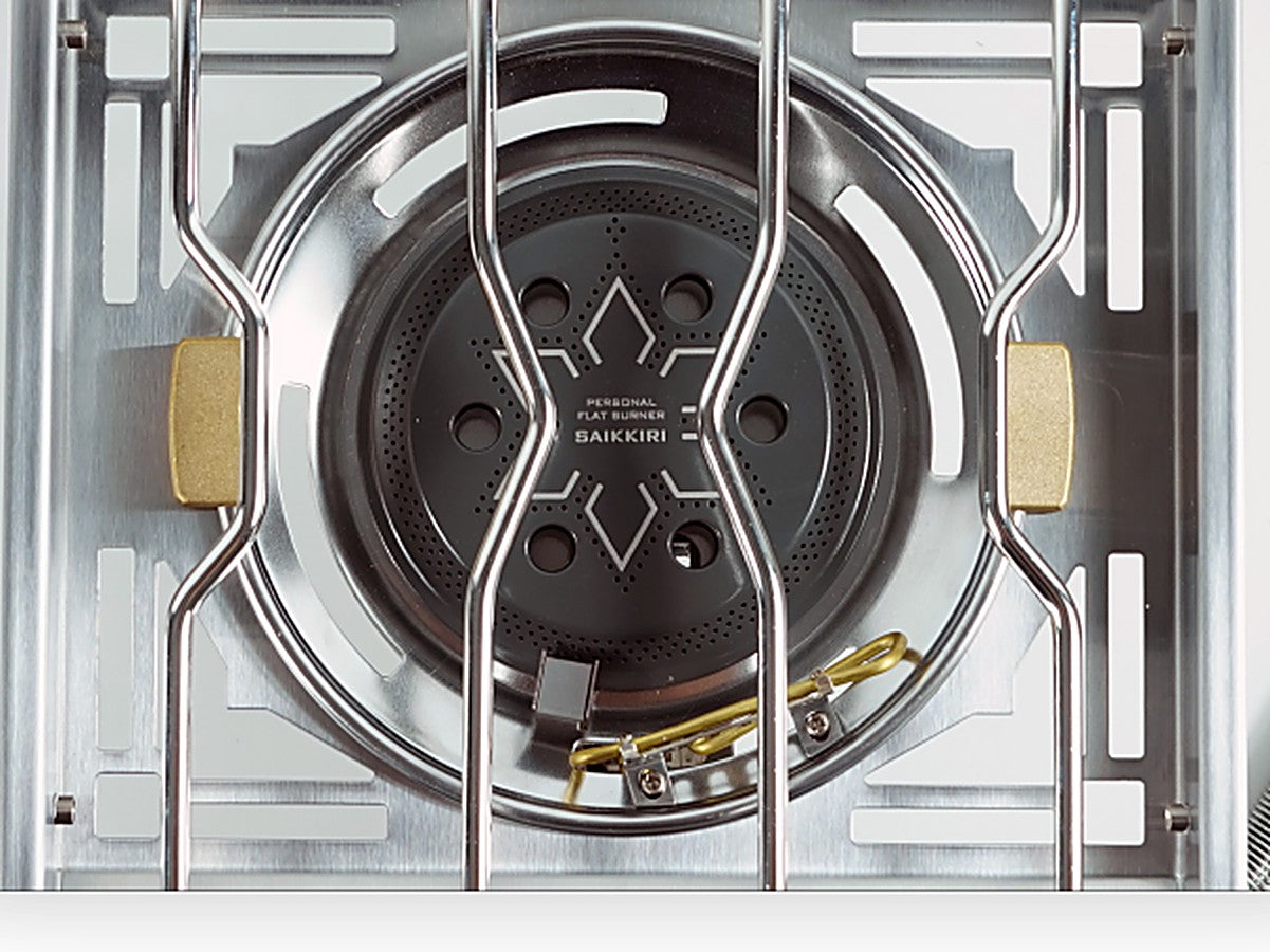 Close-up of the titanium-ceramic coated burner head with brass pot-support tabs