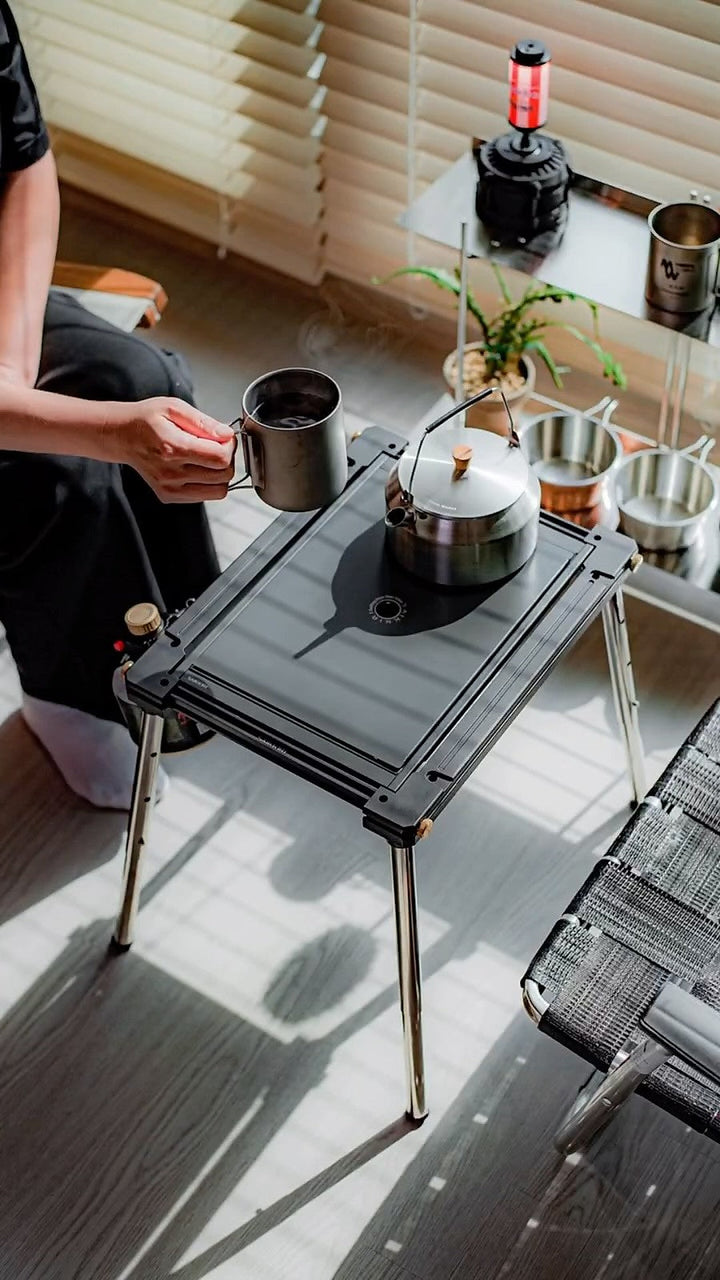 Personal Flat Burner in Black with the flat cover and a kettle in a camp coffee setup