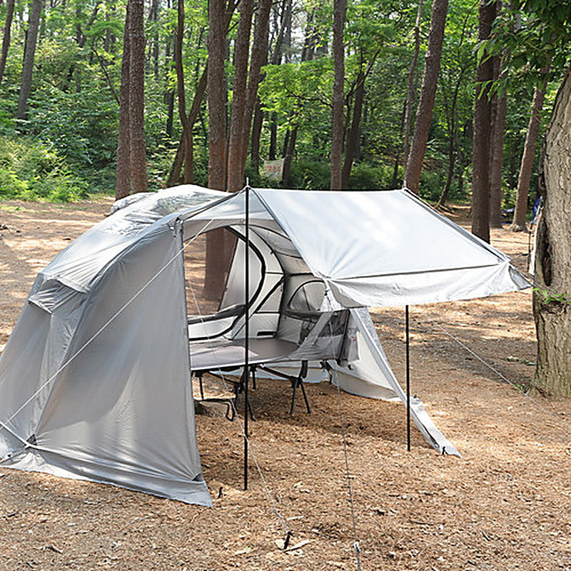 Grey Air rainfly pitched in a forest with its door raised as a canopy on two poles (tent, rainfly and cot sold separately).
