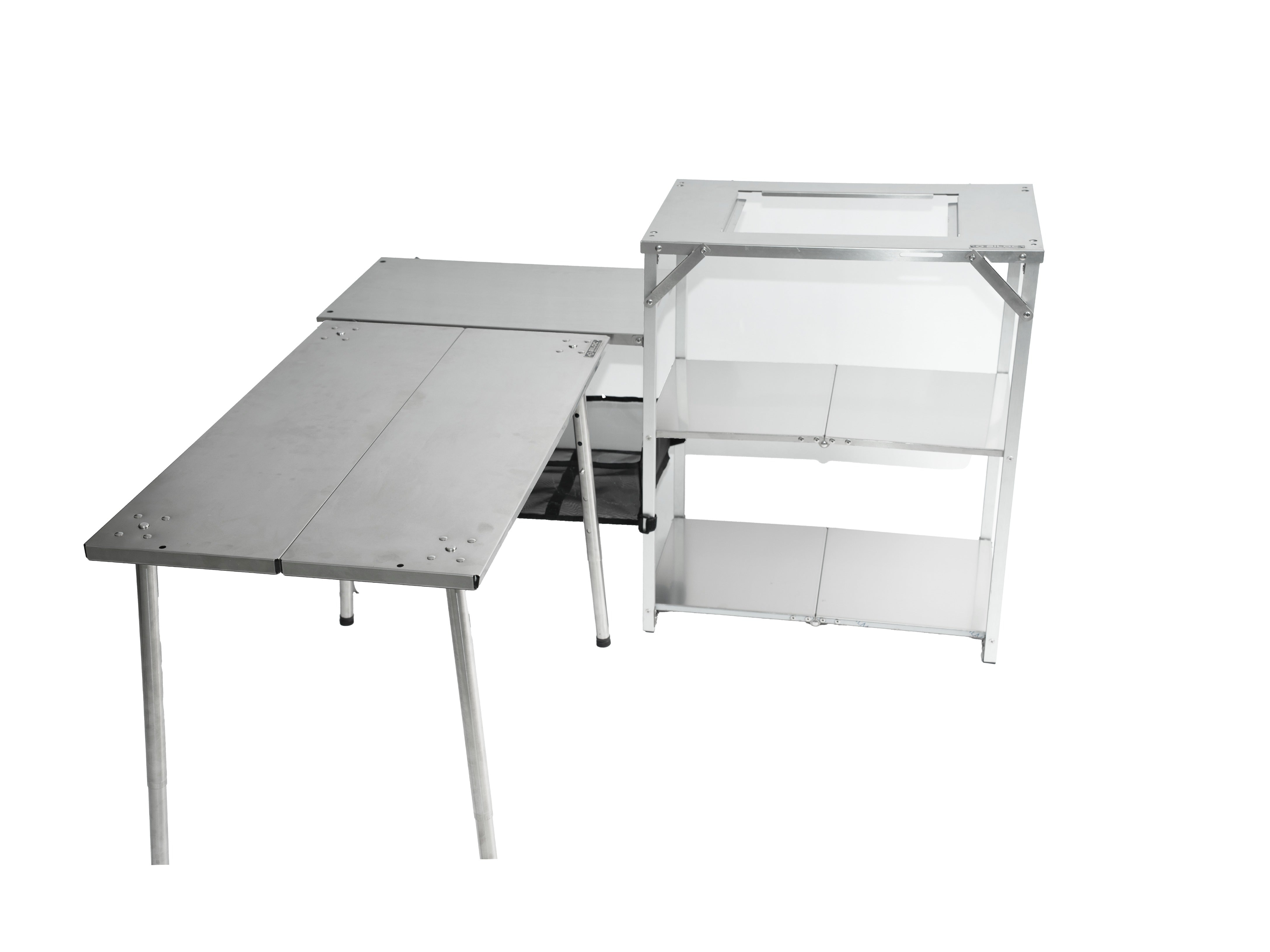 The camp shelf pushed against a long folding table so the side table and the tabletop form one continuous surface.
