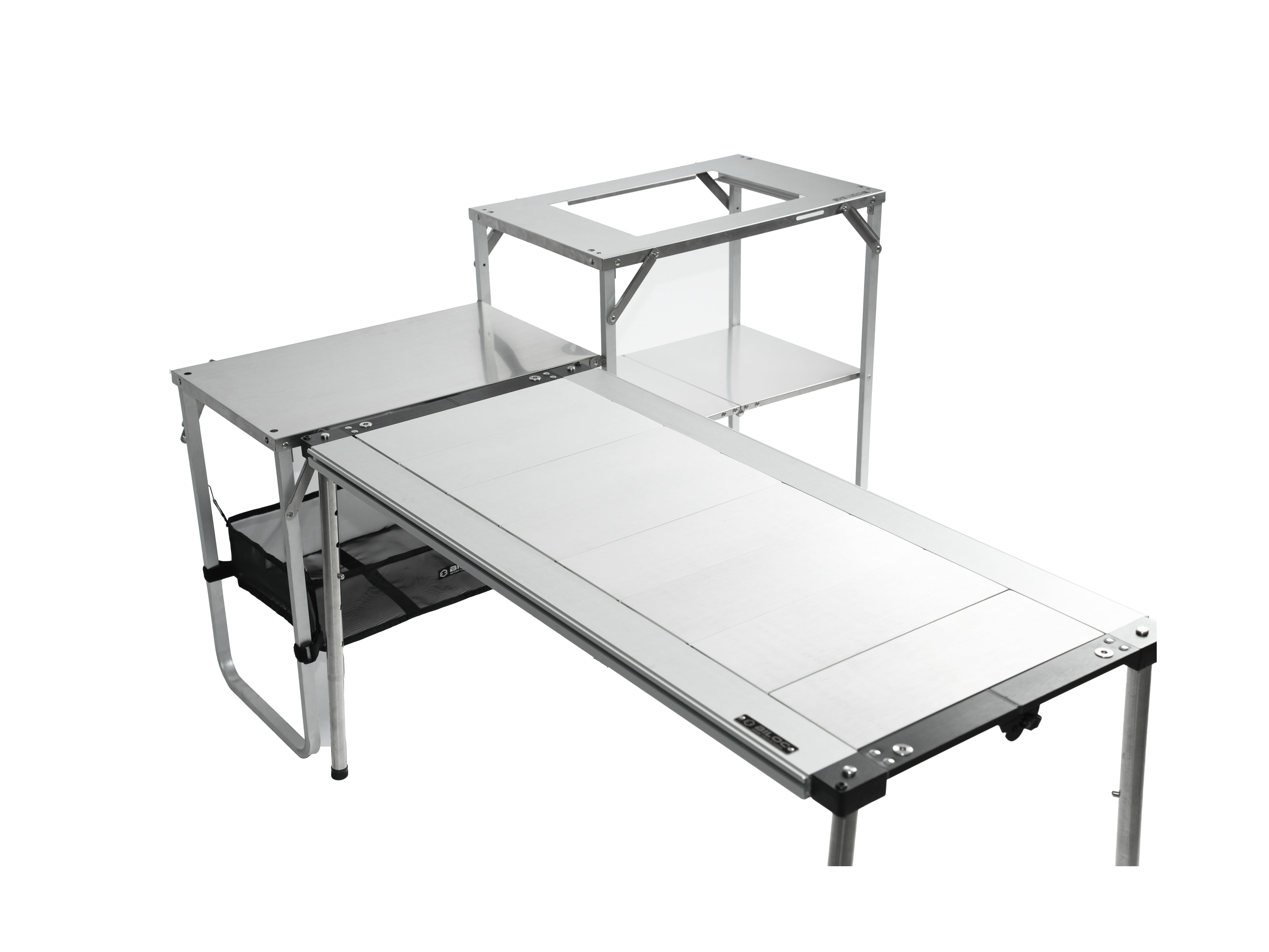 The camp shelf with its side table extended, pushed up against a long folding table so both work surfaces meet and run together in an L.