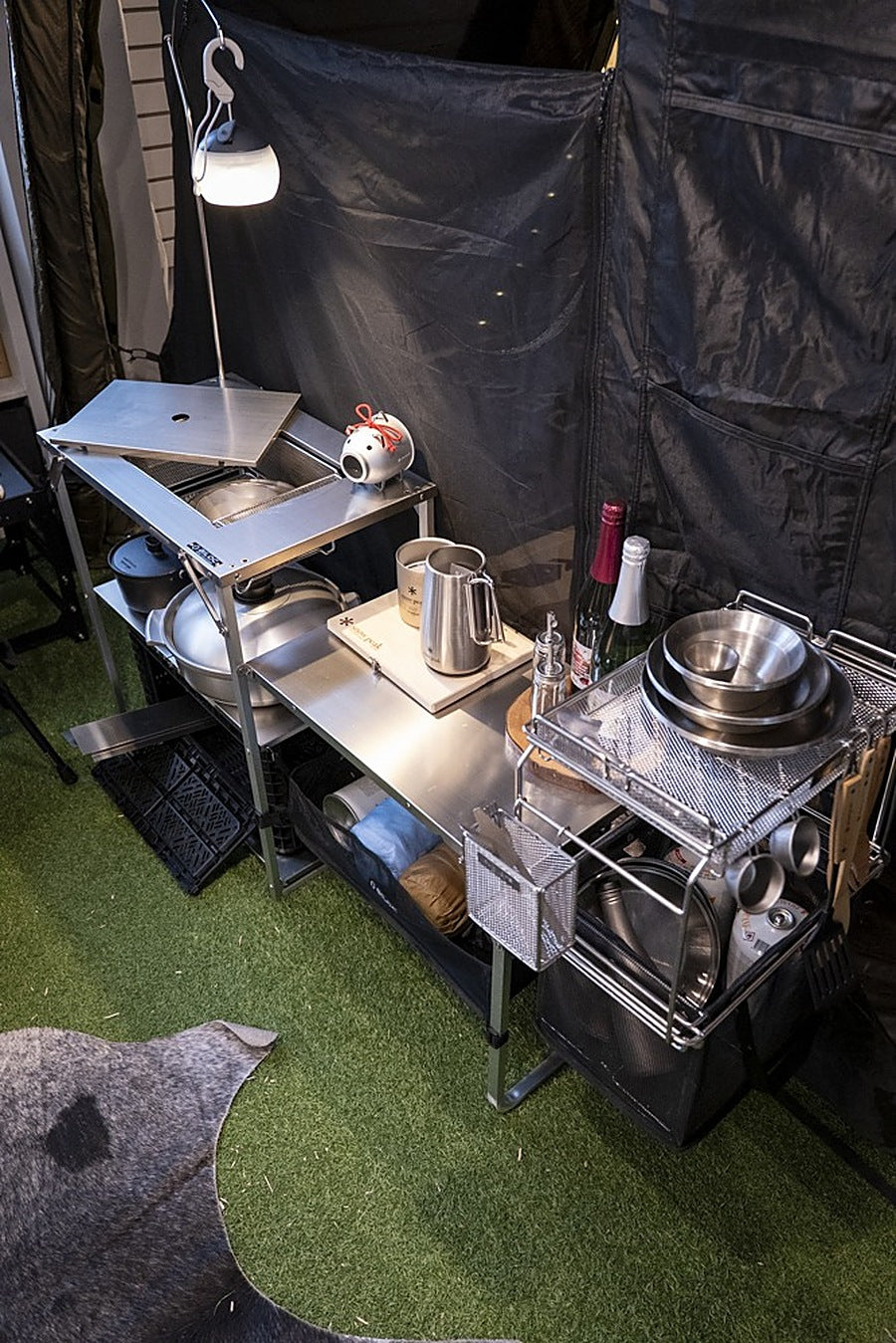 Full camp kitchen run built around the Stella shelf: crates and soft bags on the lower shelves, cookware above. The gear shown is not included.
