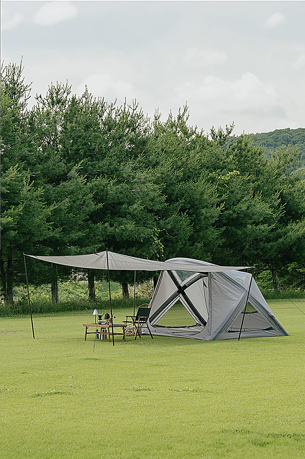 Sun shade pitched on the Geo-Air 4 with its open end raised on two poles over a table and chairs on grass