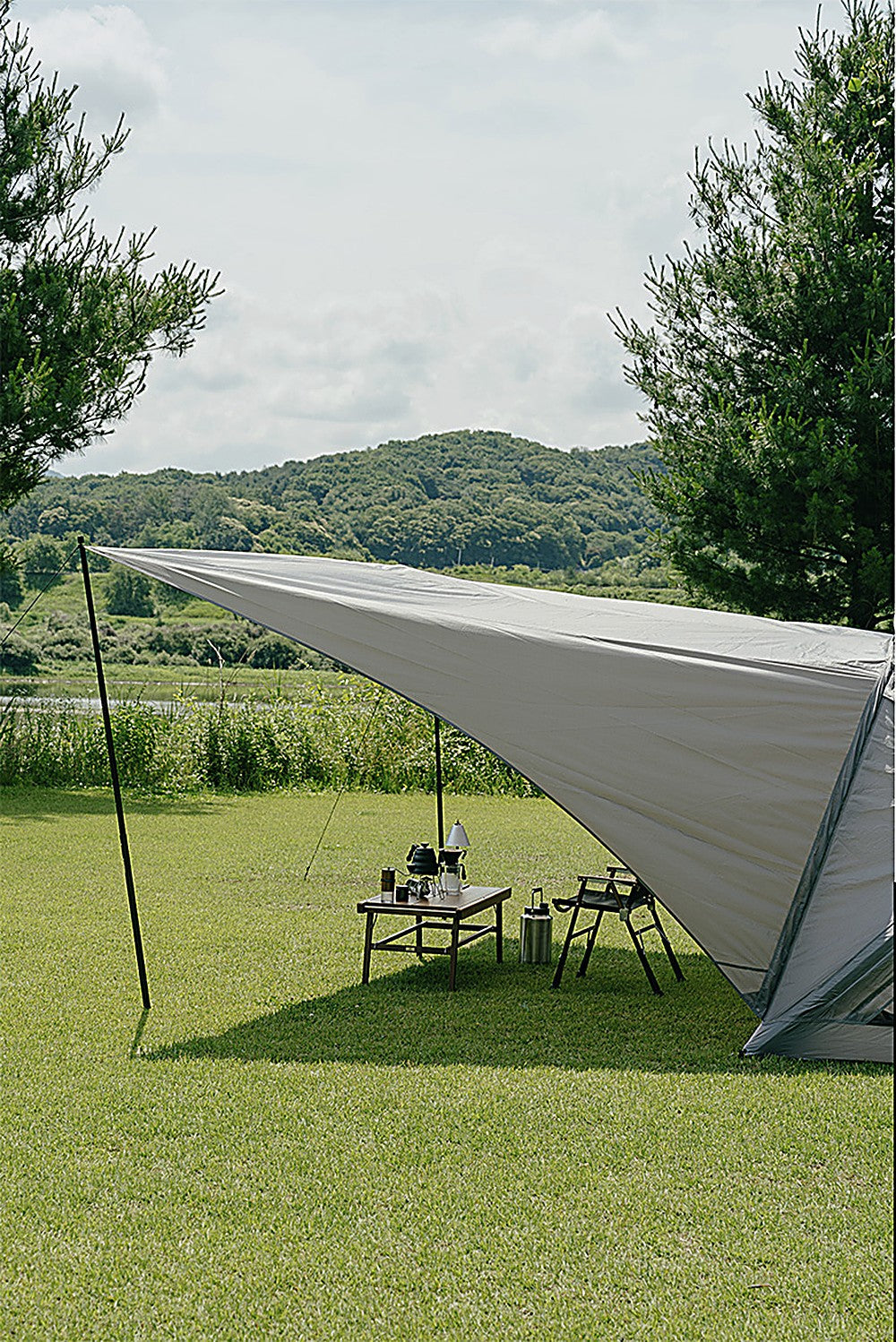 Sun shade and Geo-Air 4 tent pitched on an open green field under a bright sunny sky