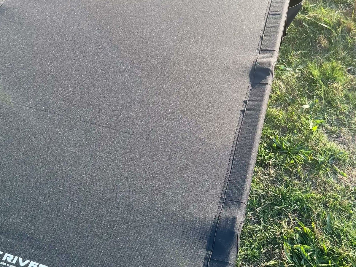 Top view of the Wide Cot 80 deck on grass, with the printed Mount River logo near the foot end.